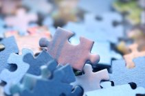 blue, purple, and pink jigsaw puzzle pieces in a disordered pile