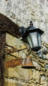 Lantern in front of a door with an old bell and a welcome sign