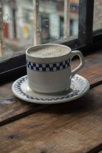 White and blue coffee cup and saucer near a window