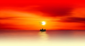 Boat at the horizon with red sky and gold water
